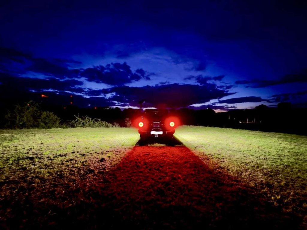 LED-Zusatzbeleuchtung für den Ineos Grenadier, auf Feld stehend und leuchtet links und rechts, durch seitliche Beleuchtung